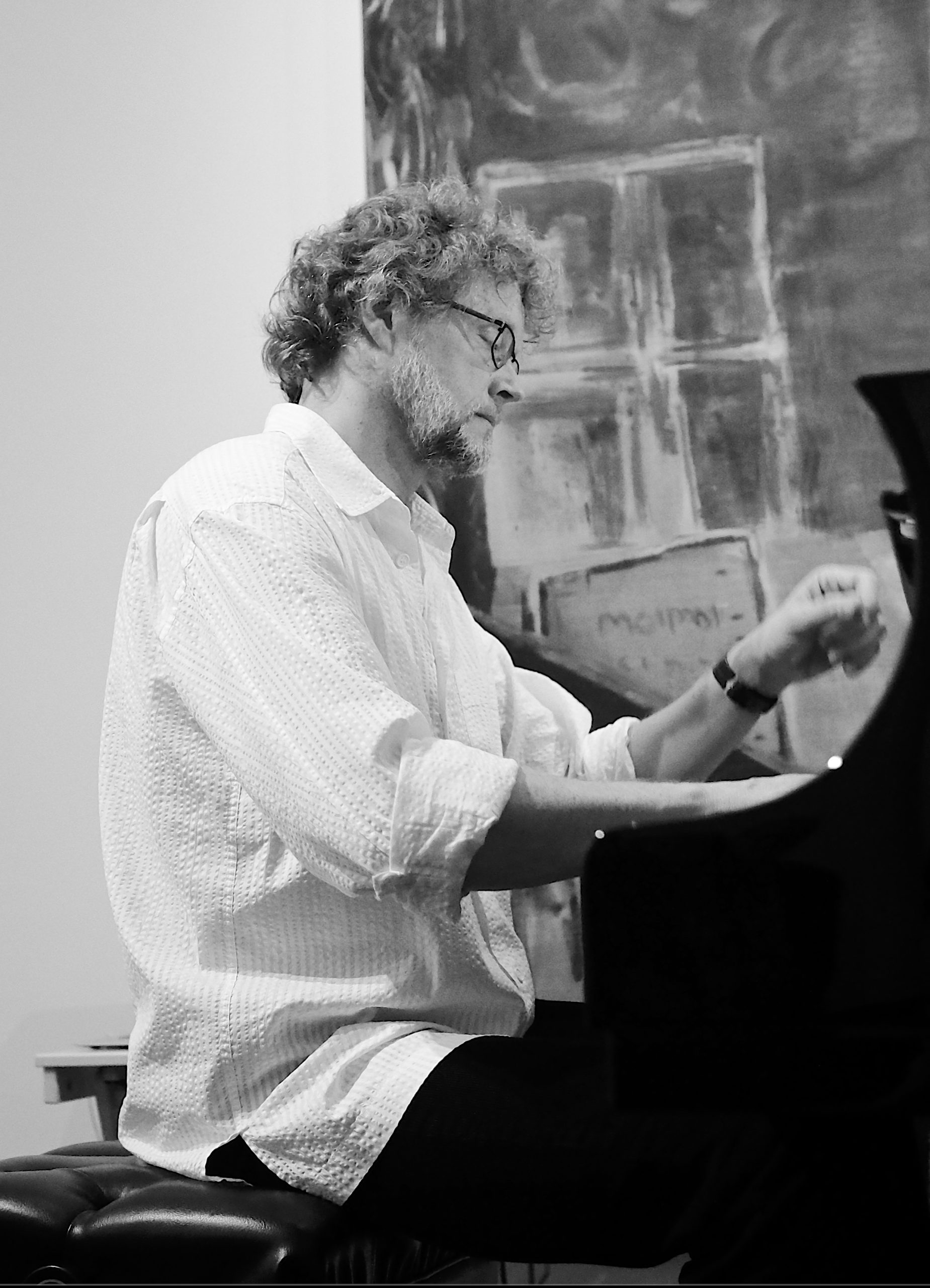 Xak Bjerken playing the piano in front of an abstract painting